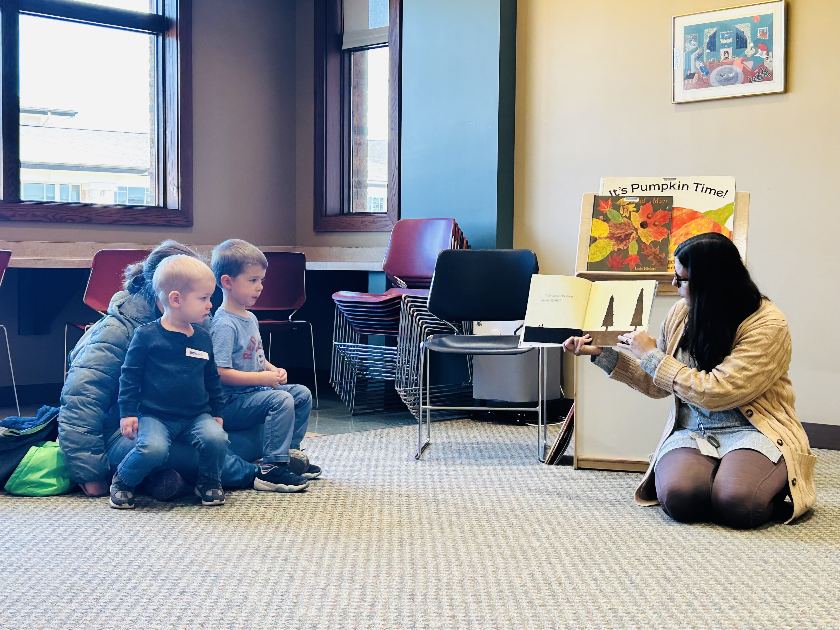 Librarian sitting on floor reading a story to a family