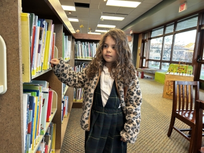 Young girl browsing the library stacks in the Children's Department