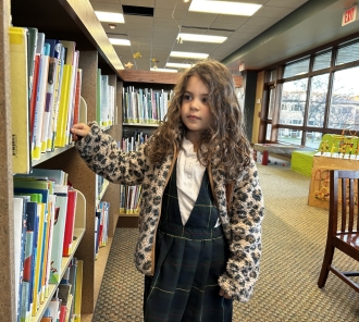 Young girl browsing the library stacks in the Children's Department