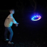 boy throwing a glowing frisbee in the dark