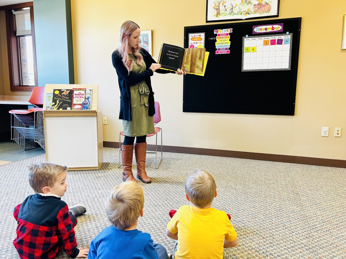 Librarian reading a book to a group of children